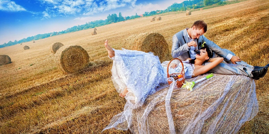 Женщина за 40 позирует в поле на сеновале из тюков