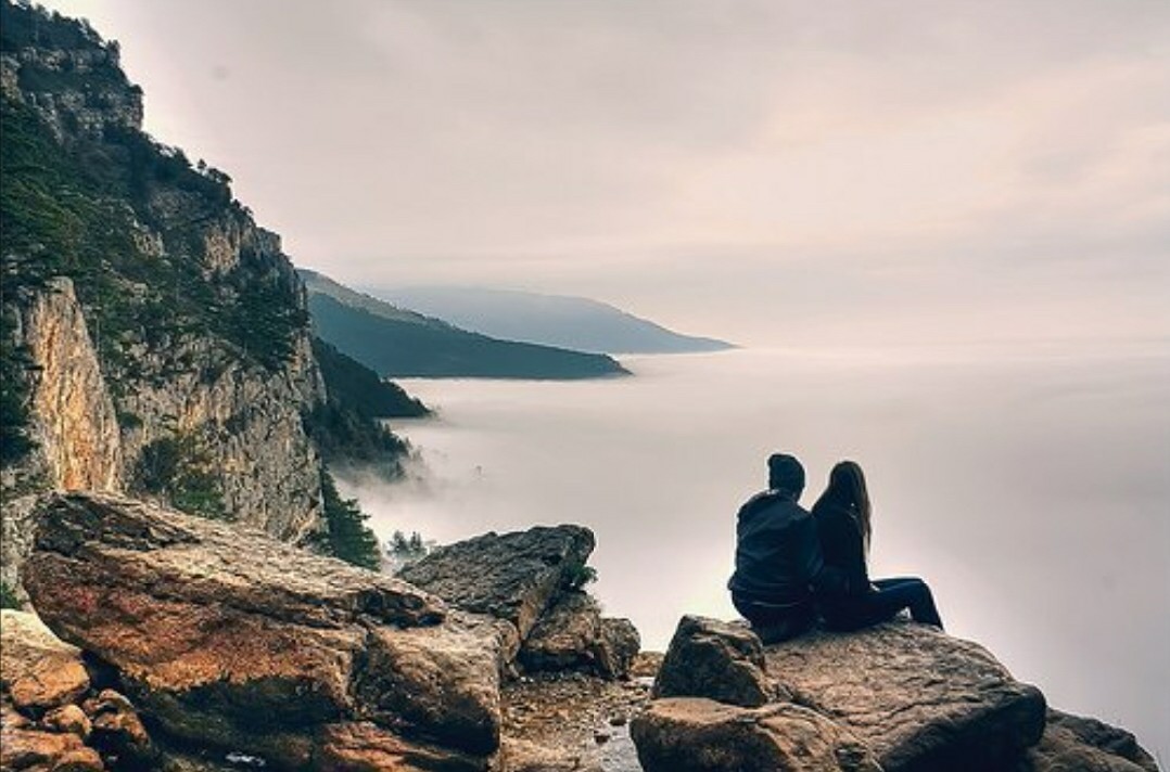 На край света в направлении. Человек на скале. Человек сидит на скале. Пара на скале. Парень и девушка на скале.