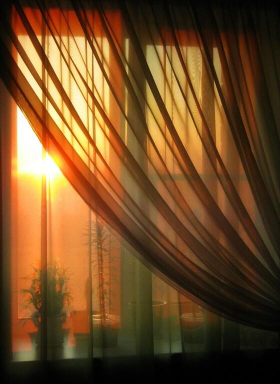Яркое солнце светит в окна домов. Луч солнца в окне. Солнце сквозь шторы. Лучи солнца в комнате. Солнечные лучи в окне.