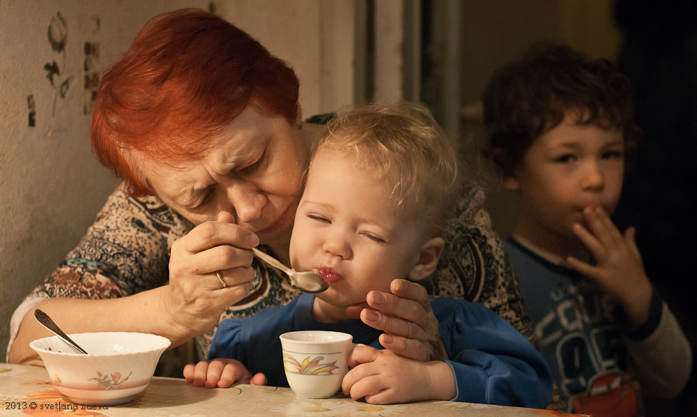 Бабушка хочет быть мамой. Бабушка и внуки. Бабушка и внук за столом. Бабушка кормит внука. Родители закармливают ребенка.