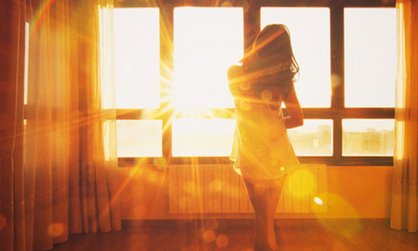 Девушка в солнечных лучах у окна