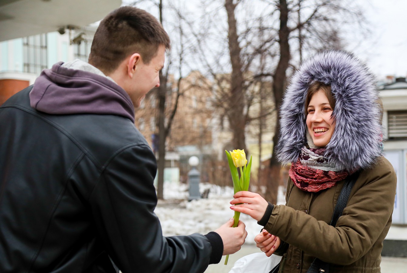 На улице дарят цветы. Женский день. Дарит цветы прохожим.