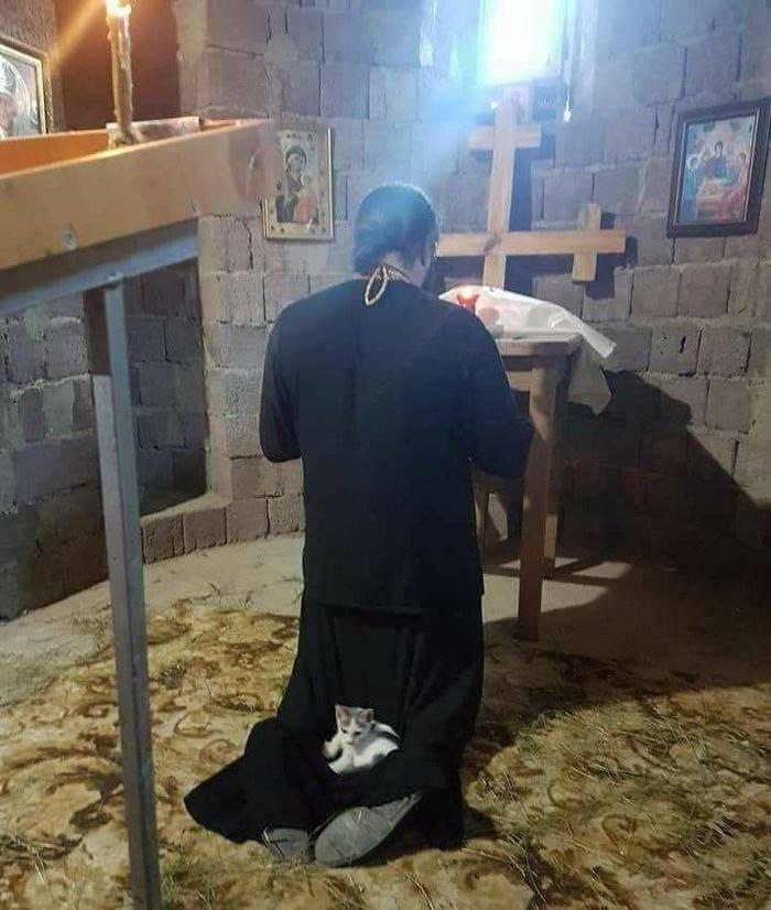 Молится батюшка возле креста